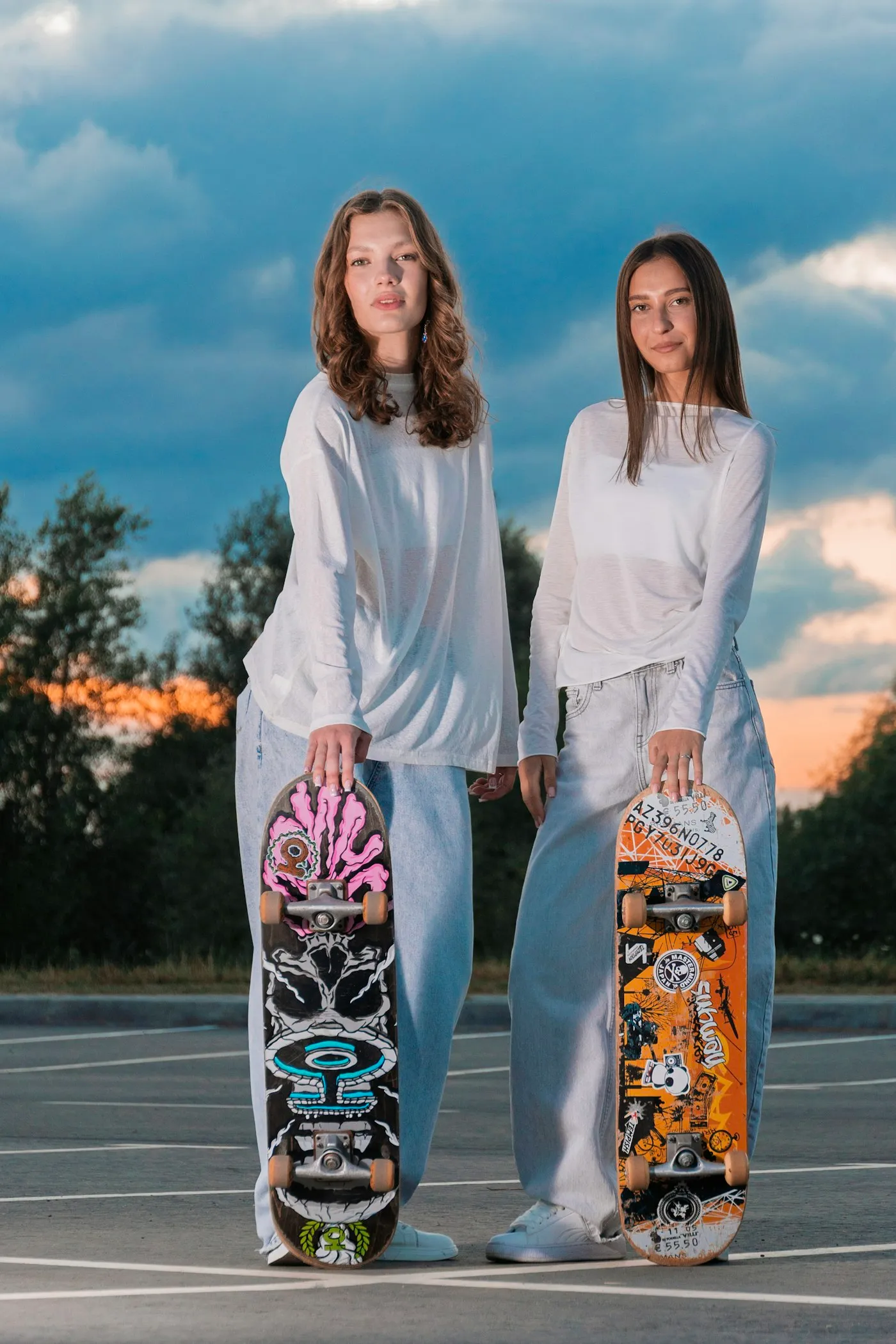 Two young people holding skateboards at sunset